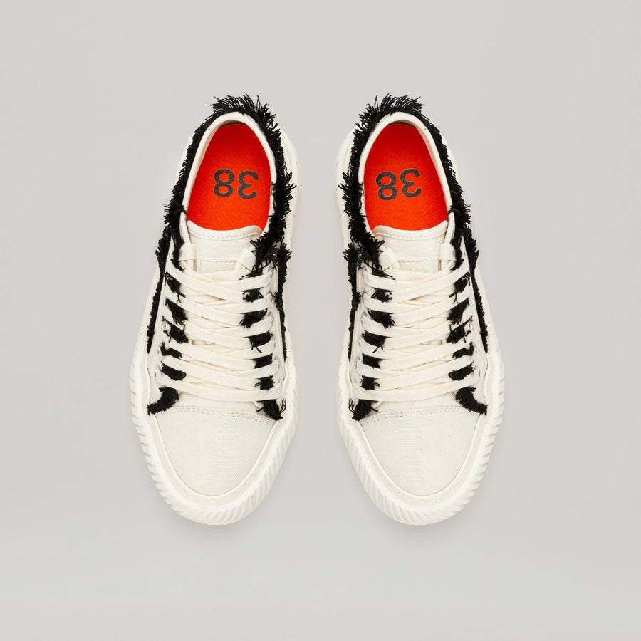 both FORMULA LOW white canvas sneakers with black fringe hem and durable EVA rubber sole