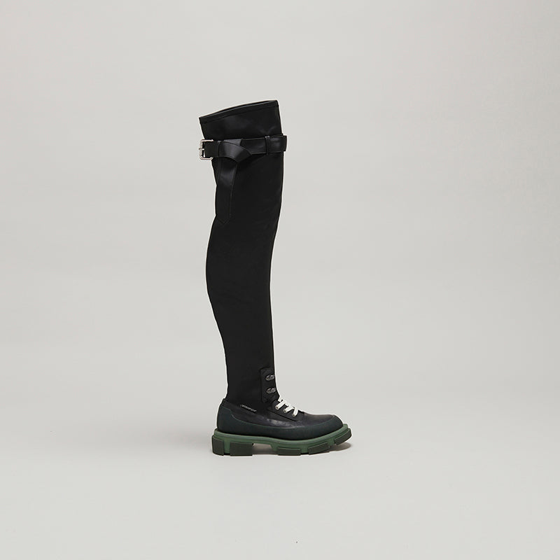 both X MONSE thigh-high boot in black with army green sole and lace-up detail