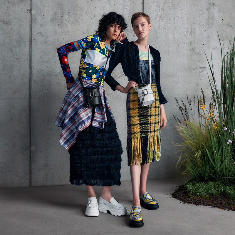 Two models showcasing both x CHARLES & KEITH platform buckled loafers in a modern fashion setting