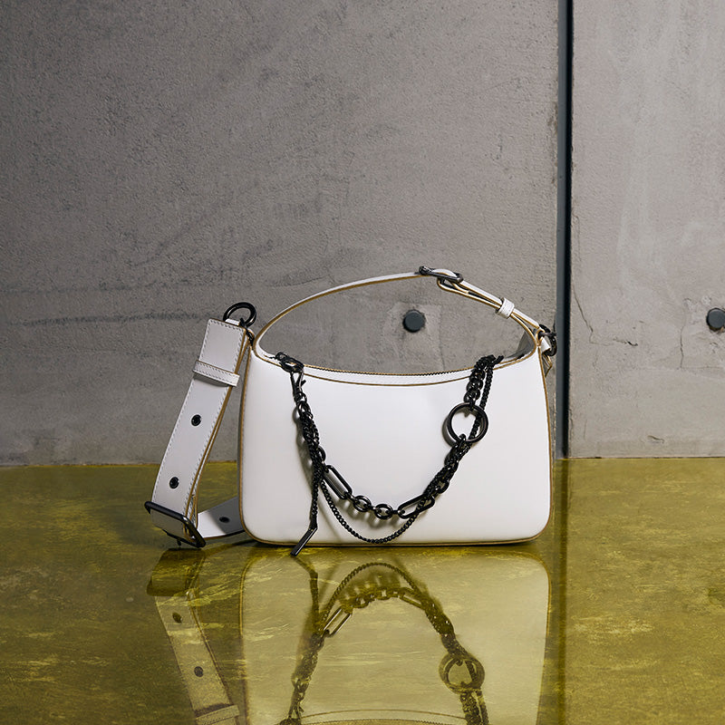 both x CHARLES & KEITH white embellished bag with black chain detail on reflective surface