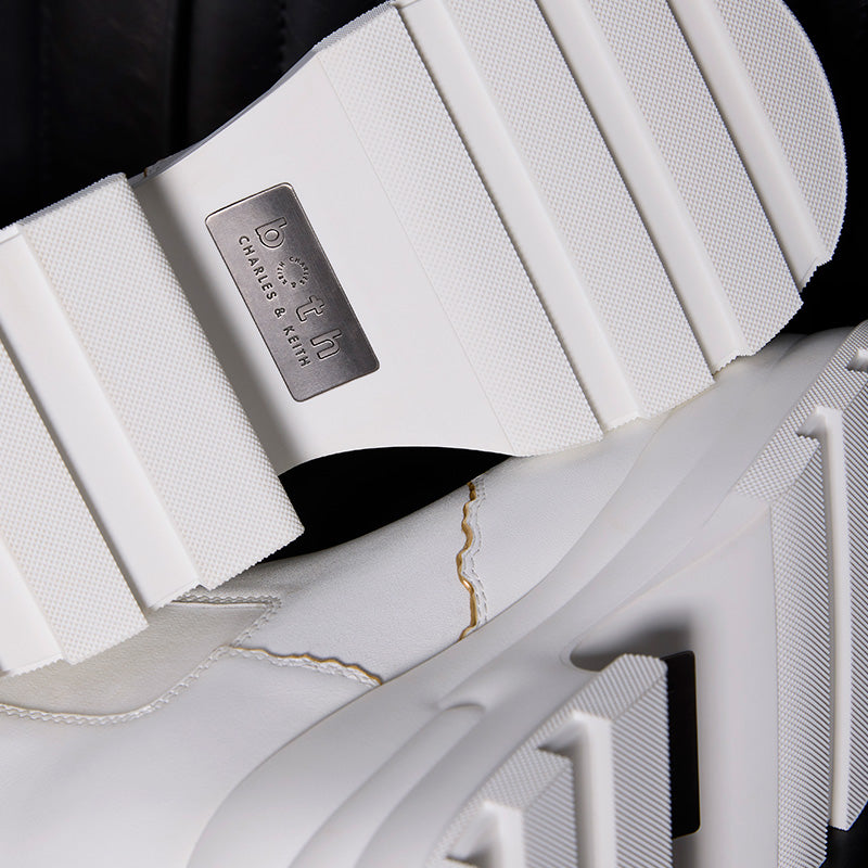 Close-up of both x CHARLES & KEITH white Chelsea boots sole with logo plate and textured tread design