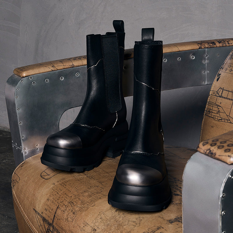 both x CHARLES & KEITH black Chelsea boots with elastic side panels and chunky soles on a vintage chair
