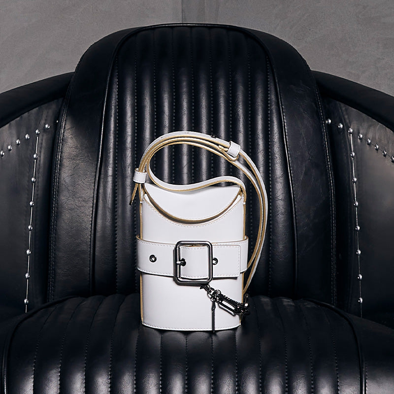both x CHARLES & KEITH white bucket bag with buckle detail on black leather chair